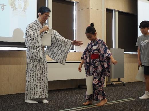 江戸の町娘に成りきるために膝の間に紙を挟んで歩きます
